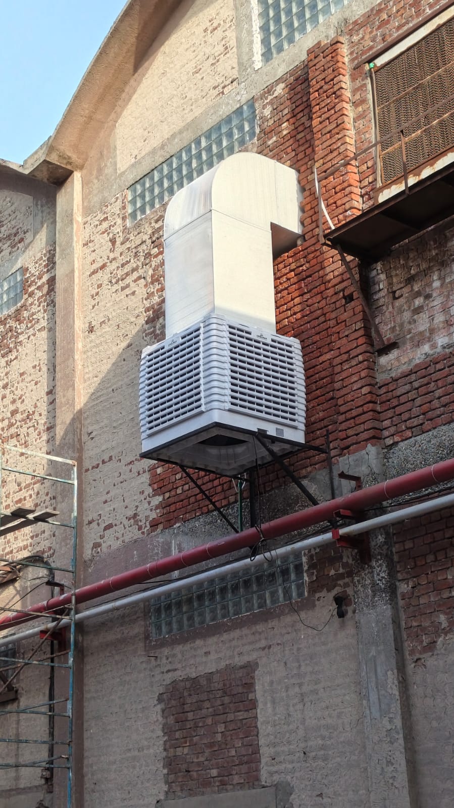 Wall-mounted cooler with duct on a brick industrial building