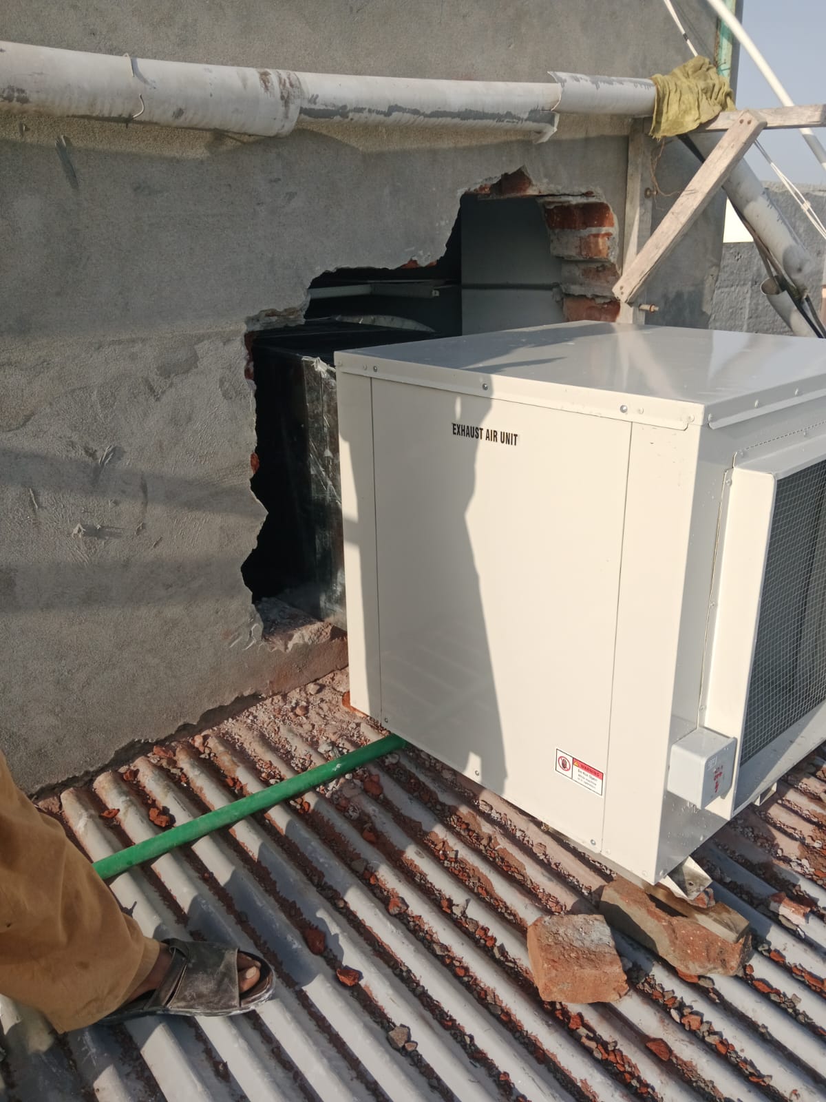Exhaust air unit installed through a wall opening on a roof