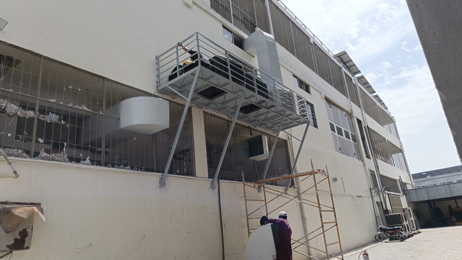 ZRS team installing air coolers on a steel platform with ducting on a factory wall